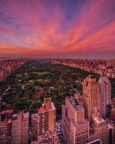 an aerial view of the city skyline at sunset, with trees and buildings in the foreground