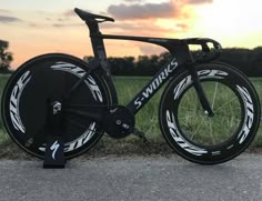 the bike is parked on the side of the road in front of some tall grass
