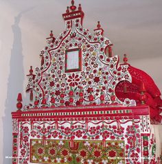 an elaborately decorated red and white bed in a room