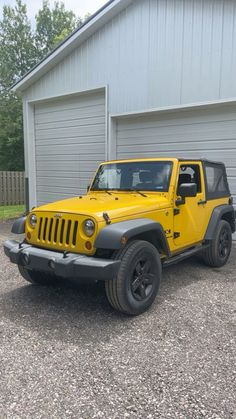 a yellow jeep parked in front of a garage