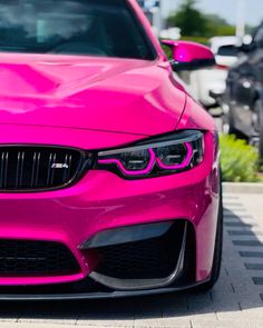 the front end of a pink bmw car