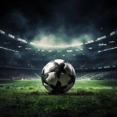 a soccer ball sitting on top of a green field in front of a large stadium