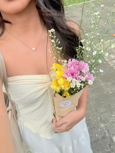 a woman holding a bouquet of flowers in her hand