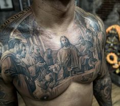 a man with tattoos on his chest is standing in front of a painting