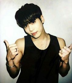 a young man with black hair giving the middle finger sign while wearing a black tank top