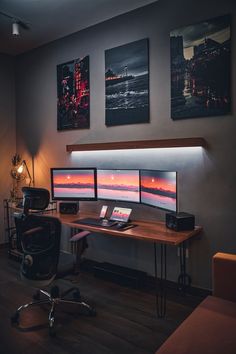 three computer monitors sitting on top of a wooden desk next to a chair and lamp