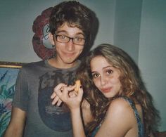 two people posing for the camera with food in their hands and one person wearing glasses