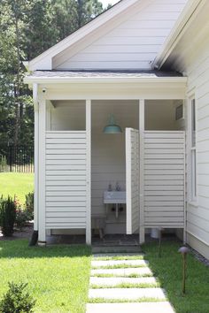 a small white house with stairs leading up to the front door and outside bathroom area