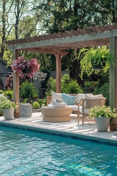 an outdoor pool with chairs and tables next to the side of it, surrounded by greenery