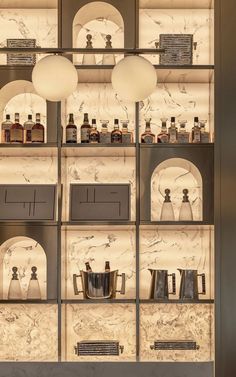 the shelves have many bottles on them and lights hanging from them in front of them