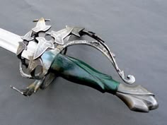 a green and silver colored metal object on a gray surface with white trimmings