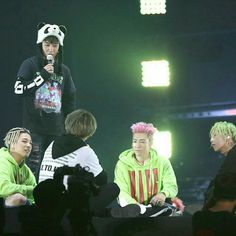 group of young men sitting on stage with microphones in their hands and one man wearing a panda hat