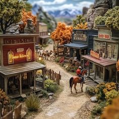 a toy town with horses and people on the street, mountains in the back ground