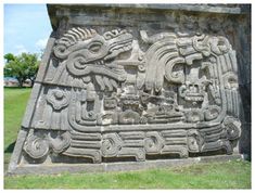 an ancient carving on the side of a building in mexico, with people walking by
