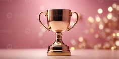 a gold trophy cup sitting on top of a table next to a pink wall with lights in the background