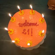 a birthday cake with candles on it that says welcome 21 / 1 and is decorated with daisies