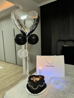 a birthday cake on a table with balloons in the shape of a heart and a card