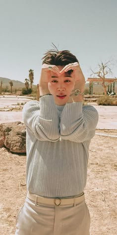 a woman standing in the desert with her hands on her head