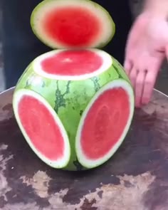 a person cutting into a watermelon fruit sculpture