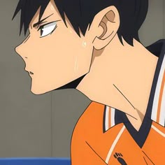 a man with black hair and an orange shirt stares at something in the distance while standing next to him