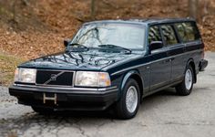 an old volvo wagon parked on the side of the road in front of some trees