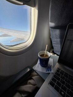 a cup of coffee sitting on top of a table next to a laptop computer