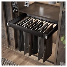 an open drawer in a closet filled with folded shirts and pants next to a wooden shelf