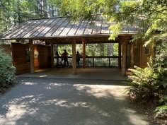 two people are standing at the top of a gazebo surrounded by trees and bushes