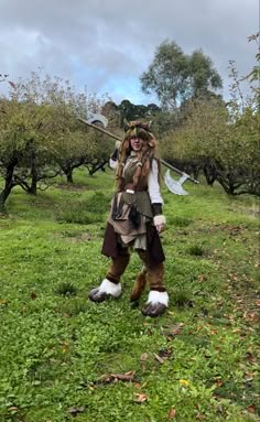 a man dressed in costume standing on top of a lush green field next to trees
