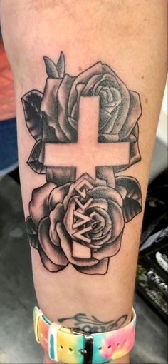 a cross and roses tattoo on the leg