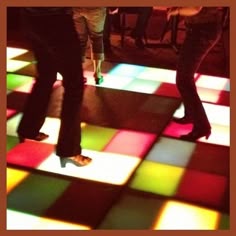 two people standing on a multicolored dance floor