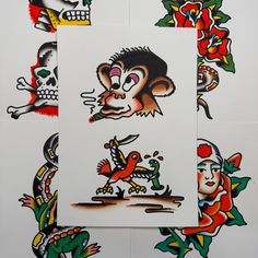 four different colored tattoos on white paper with skulls and flowers in the middle one has a monkey holding a knife