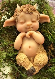 a small statue of a little boy laying down in the grass with his eyes closed