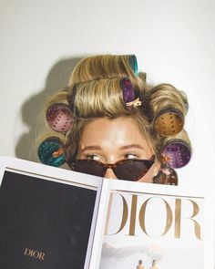 a woman is reading a magazine with her hair in rollers on top of her head