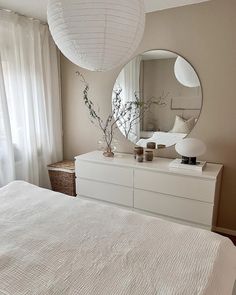 a white bed sitting under a large round mirror