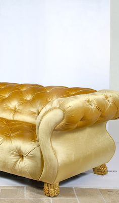 a gold couch sitting on top of a tile floor next to a white wall in a room