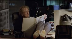 a woman sitting in an office chair reading a newspaper