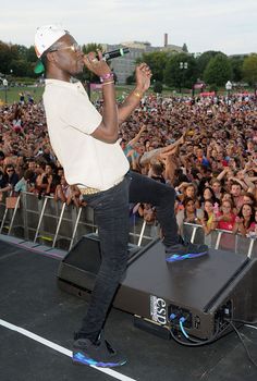a man standing on top of a stage with a microphone in front of a crowd