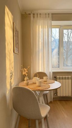 a dining room table with two chairs and a small round table in front of a window
