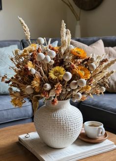 a white vase filled with flowers on top of a table next to a blue couch