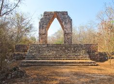 an old stone structure with steps leading up to it in the middle of a forest