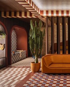 an orange couch sitting on top of a checkered floor next to a potted cactus