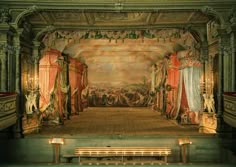 an ornate stage with benches and paintings on the walls