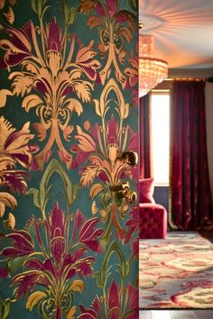 an ornately decorated room with pink and green wallpaper, chandelier and red velvet chairs