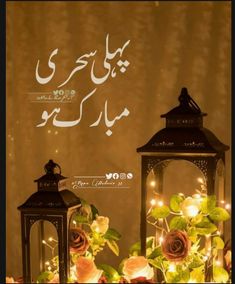 two lanterns sitting next to each other with roses on the table in front of them