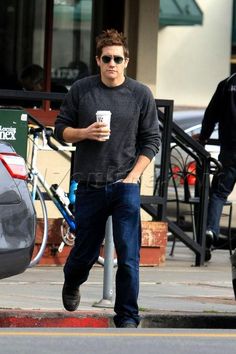 a man walking down the street while holding a coffee cup