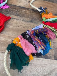 several different colored pieces of cloth on a wooden floor with rope and thread around them