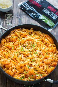 pasta with shrimp and parmesan cheese in a skillet on a wooden table