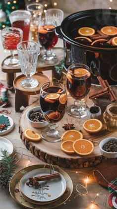 the table is set with orange slices, wine glasses and cinnamons for christmas dinner