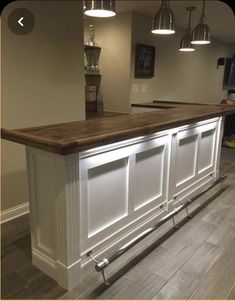 a kitchen with an island in the middle of it and lights hanging from the ceiling